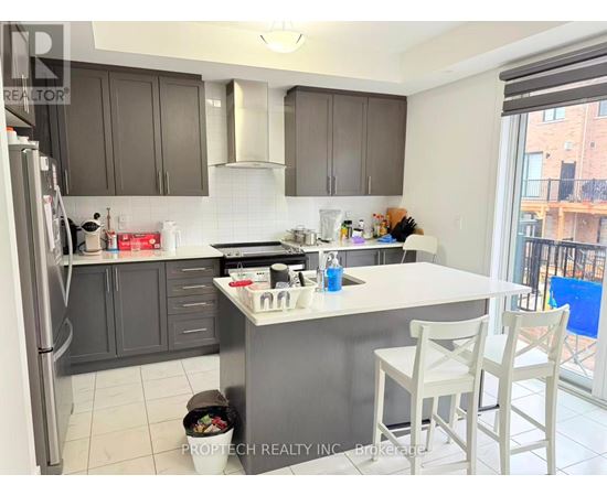A kitchen with a refrigerator, sink, and a dining table with chairs.
