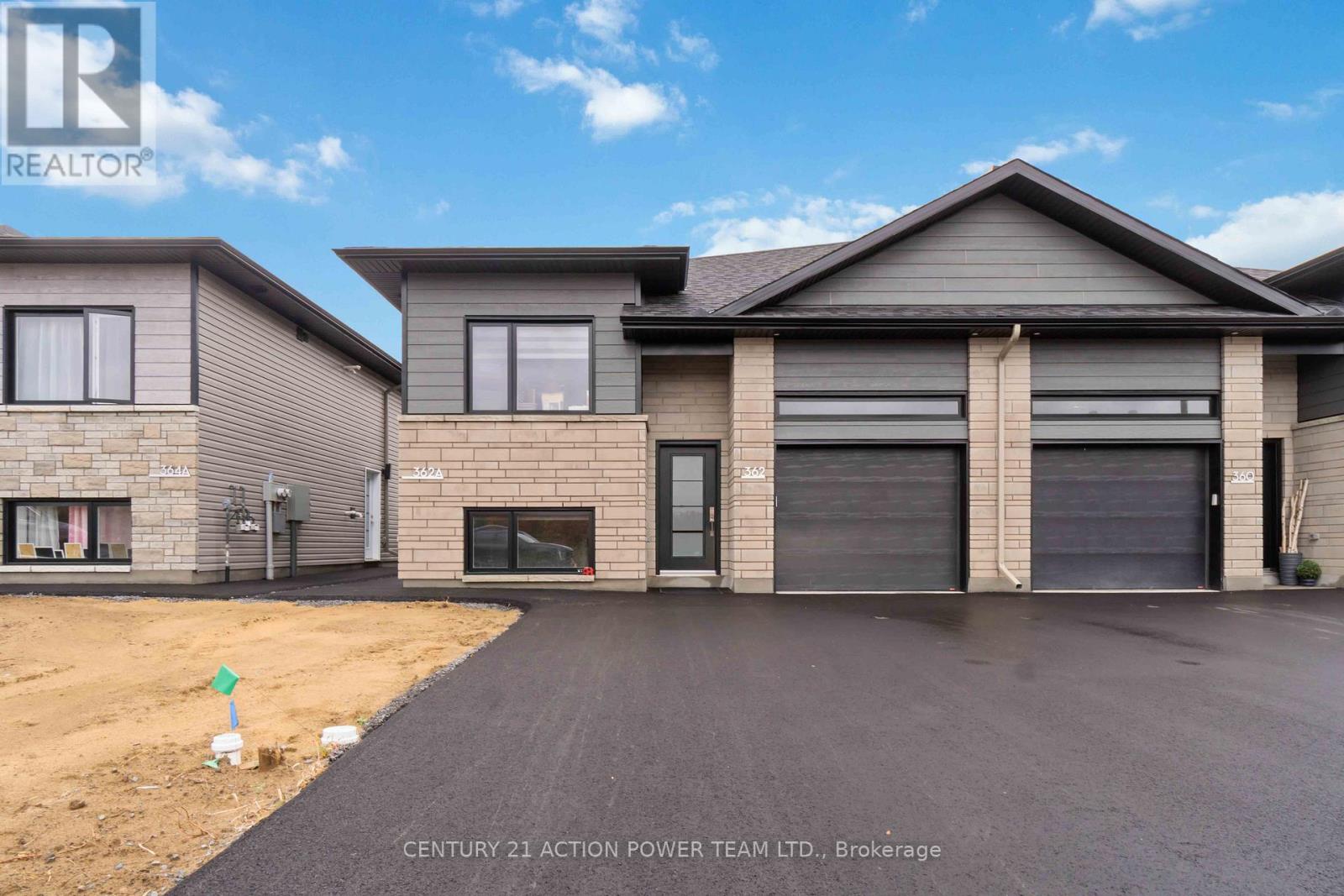 A real estate photo of a house with a grey roof and a black garage door.