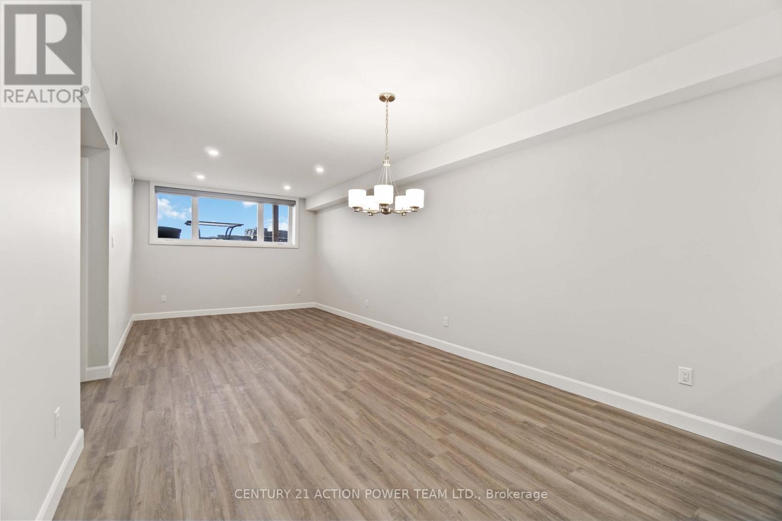 A spacious room with wooden flooring and a large window.