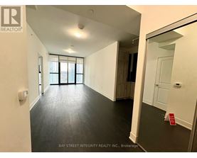 A spacious room with a large window and a door leading to another room.