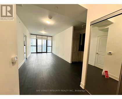 A spacious room with a large window and a door leading to another room.