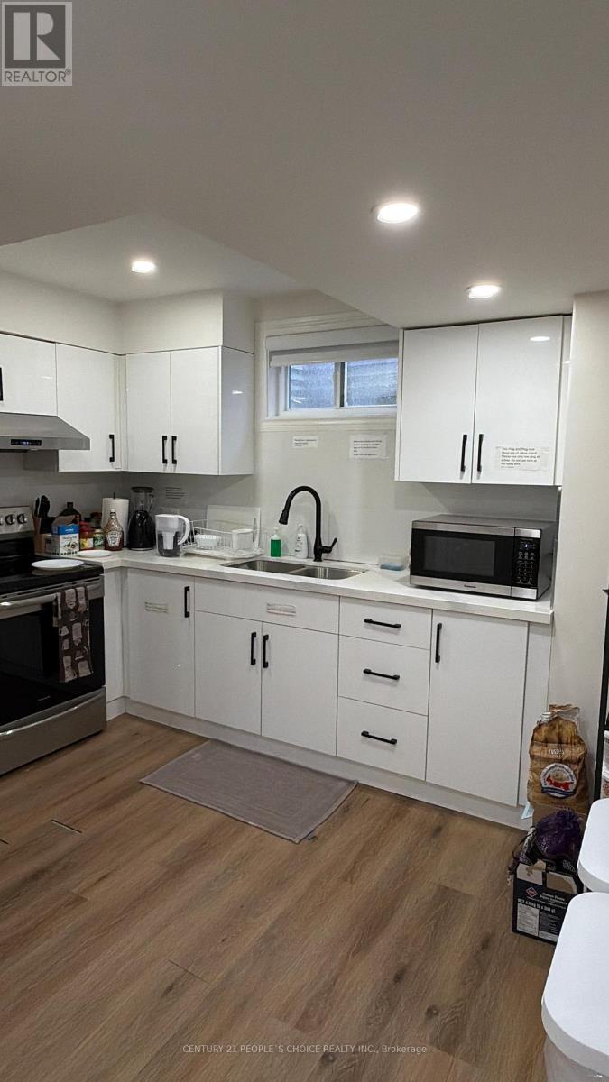 A kitchen with white cabinets and a wooden floor.