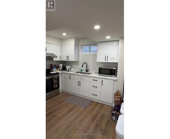 A kitchen with white cabinets and a wooden floor.
