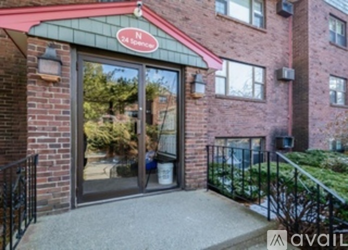 The entrance to a building with a red awning and a sign that reads "N 24 Spence.".