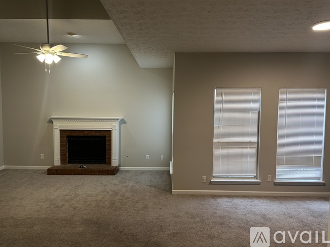A living room with a fireplace and a ceiling fan.