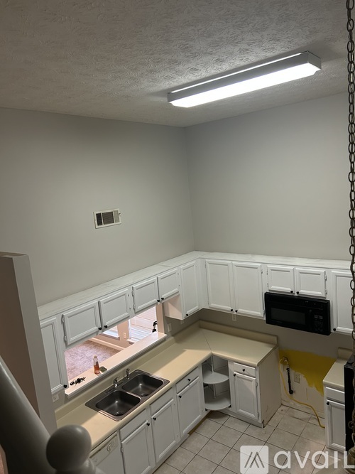 A kitchen with white cabinets and a black microwave.