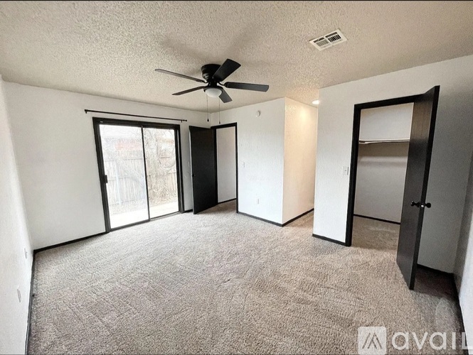 A room with a ceiling fan and sliding glass doors.