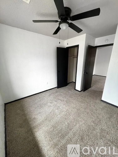 A room with a ceiling fan and carpeted floor.