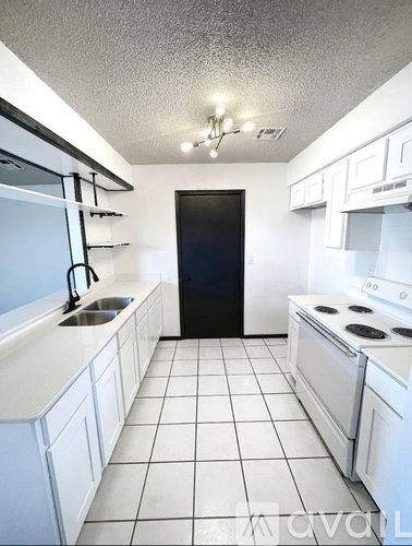 A kitchen with white cabinets and a black refrigerator.