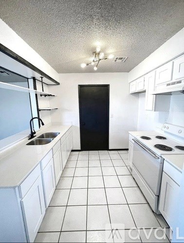 A kitchen with white cabinets and a black refrigerator.