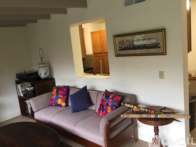 A living room with a couch, a coffee table, and a painting on the wall.