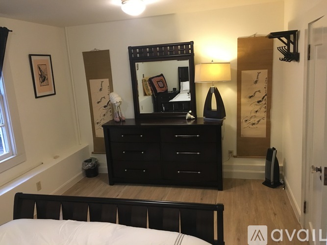 A bedroom with a black dresser and a large mirror.