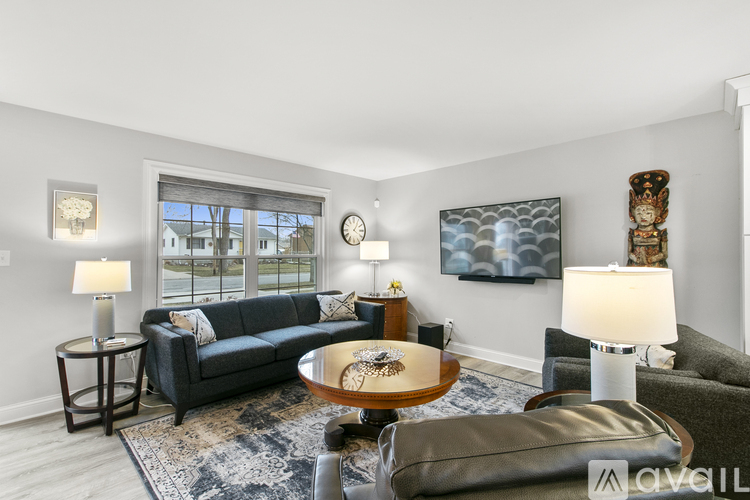 A living room with a grey couch, a coffee table, and a painting on the wall.
