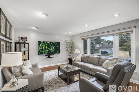 A living room with a grey couch, a coffee table, and a large painting on the wall.