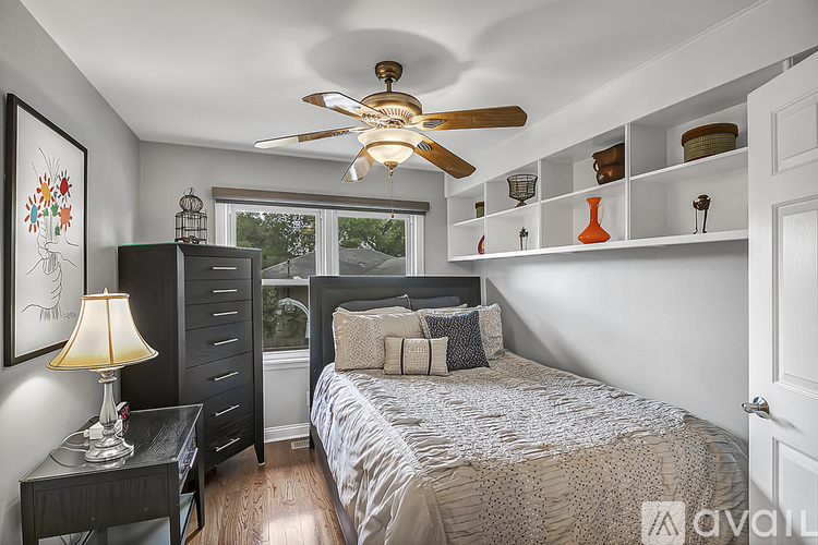 A bedroom with a bed, dresser, and a ceiling fan.