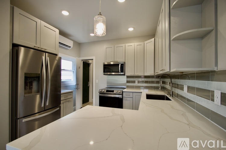 A modern kitchen with stainless steel appliances and white marble countertops.