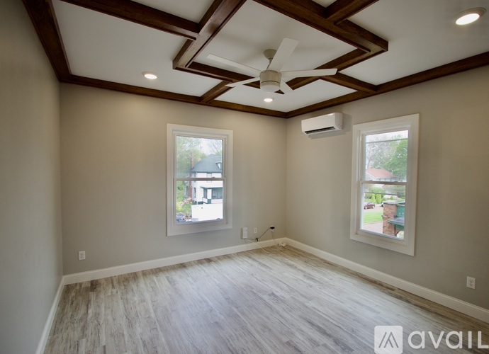 A room with a ceiling fan and two windows.