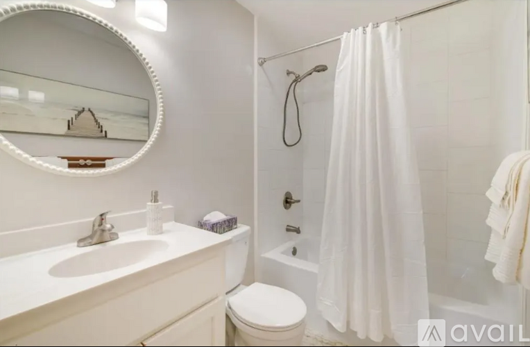 A white bathroom with a toilet, sink, and shower.
