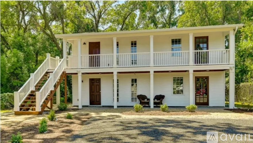 A white two-story house with a balcony and a staircase leading to the upper floor.