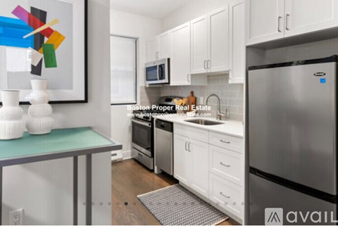 A kitchen with white cabinets and a stainless steel refrigerator.