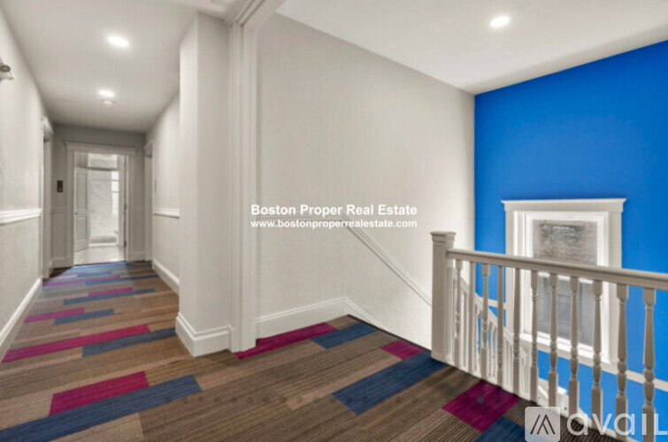 A hallway with a white railing and a blue wall.