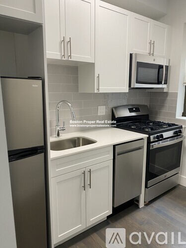 A kitchen with white cabinets and a stainless steel refrigerator.