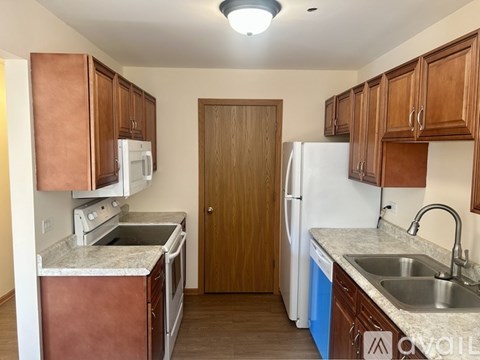 A kitchen with brown cabinets and a white refrigerator.