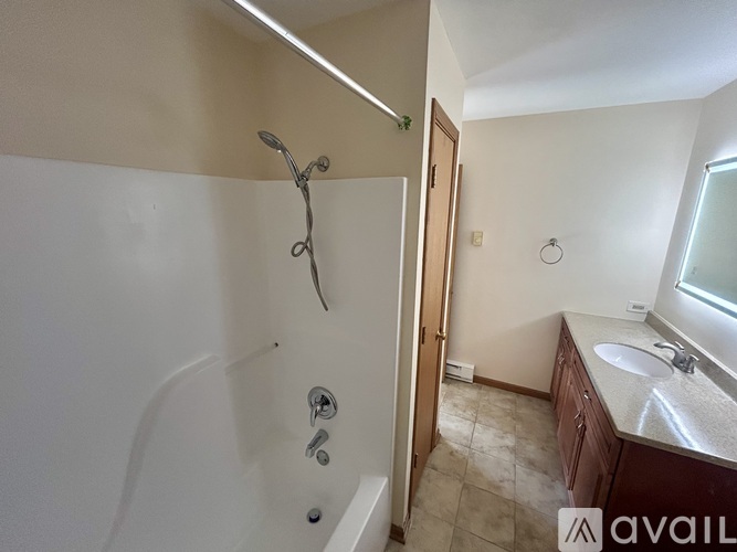 A bathroom with a white bathtub and a sink with a mirror.