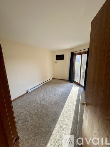 A room with a carpeted floor and a window with curtains.