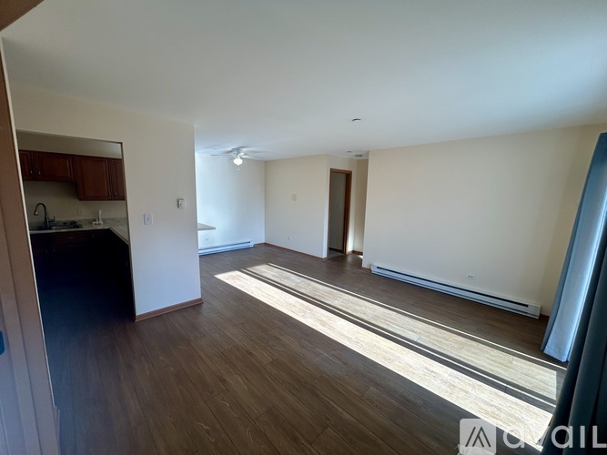 A spacious room with wooden flooring and a ceiling fan.