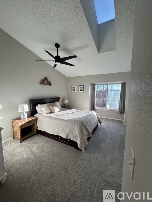 A bedroom with a bed, nightstand, and a ceiling fan.