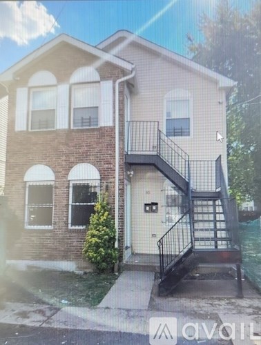 A two-story house with a balcony and a staircase leading to the front door.