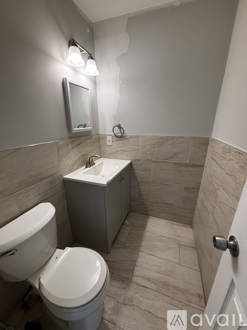 A bathroom with a toilet, sink, and mirror.