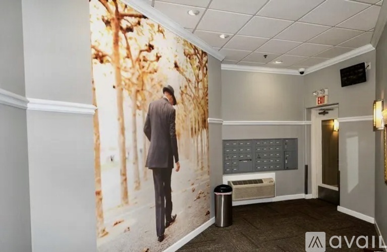 A man in a suit walks past a wall with a tree mural on it.