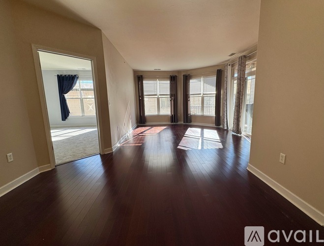 A spacious room with wooden floors and large windows.