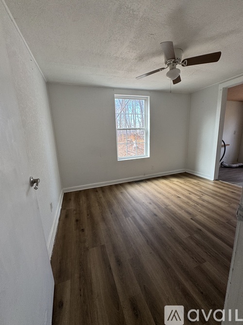 A room with wooden flooring and a ceiling fan.
