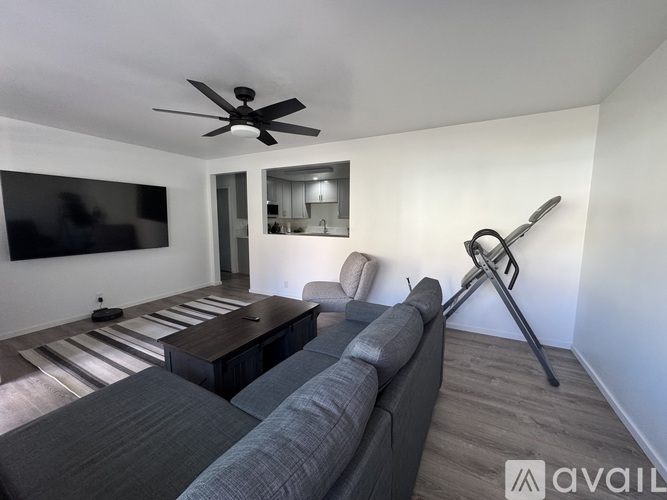 A living room with a grey couch and a black ceiling fan.