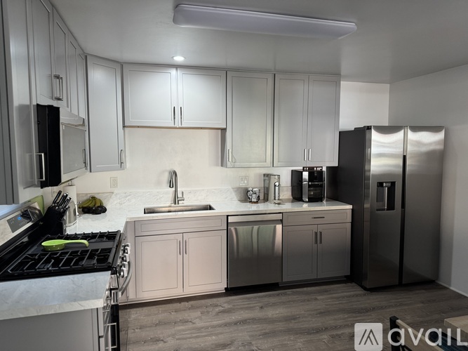 A kitchen with white cabinets and a black fridge.
