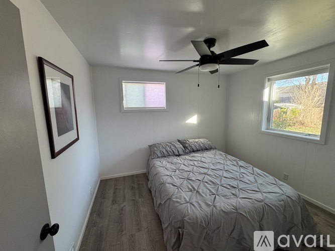 A bedroom with a bed, ceiling fan, and a window.
