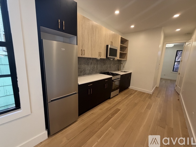 A kitchen with a stainless steel refrigerator and wooden cabinets.