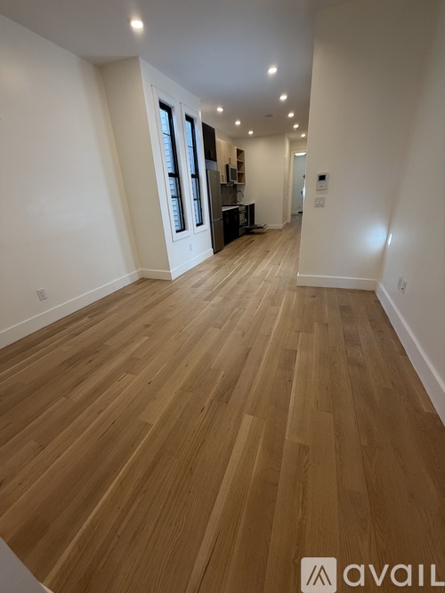 A long hallway with wooden floors and white walls.