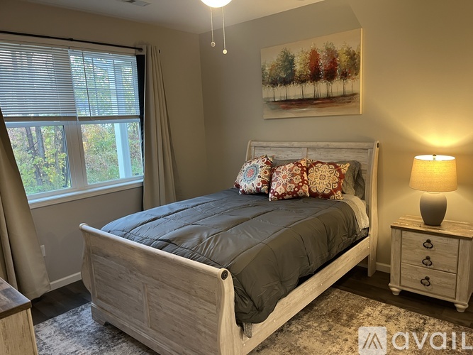 A bedroom with a bed, nightstand, and a painting on the wall.