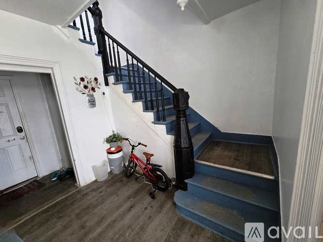 A red bicycle is parked by a staircase.