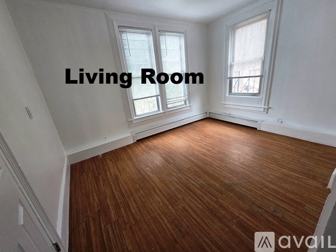 A living room with wooden floors and two windows.