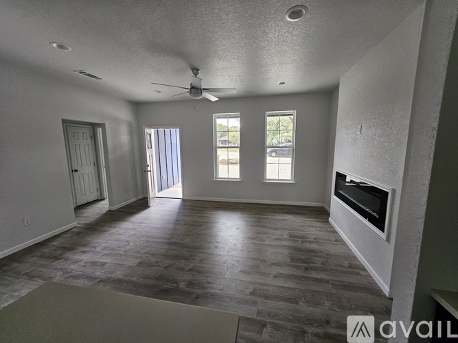 A spacious room with a fireplace and a ceiling fan.