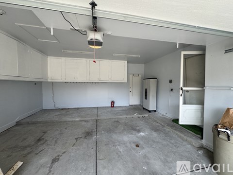 A large empty room with a white ceiling and a fire extinguisher on the wall.