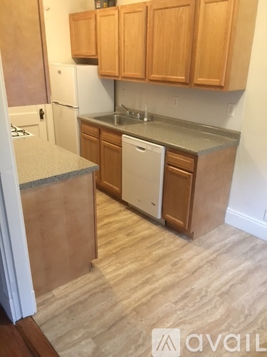 A kitchen with wooden cabinets and a white dishwasher.