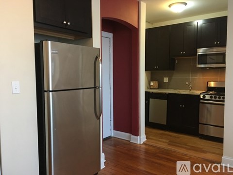 A kitchen with a stainless steel refrigerator and black cabinets.