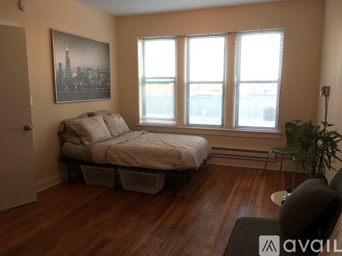 A bedroom with a bed, a chair, and a plant.