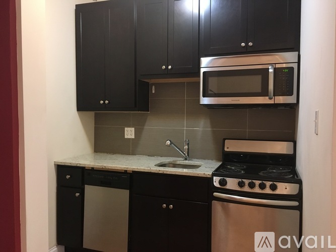 A kitchen with black cabinets and a stainless steel oven.